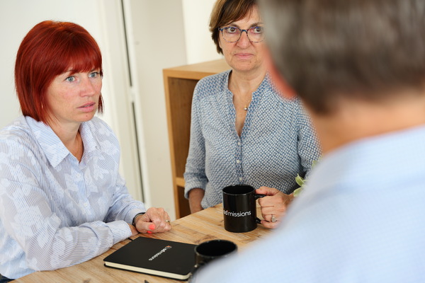 Trois personnes sont réunies autour d'une table pour discuter du portage salarial avec ADM et leur expertise de 20 ans.