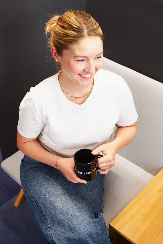 Une femme assise sur un fauteuil tient une tasse de café