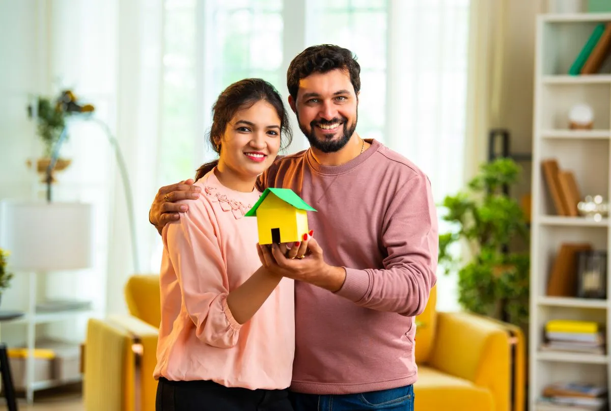 Un couple tient une petite maison