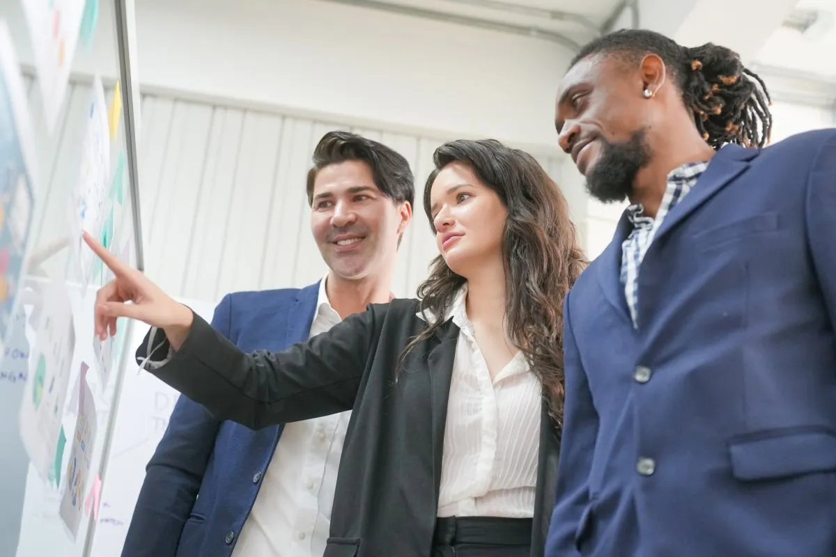 Trois employés regardent un tableau