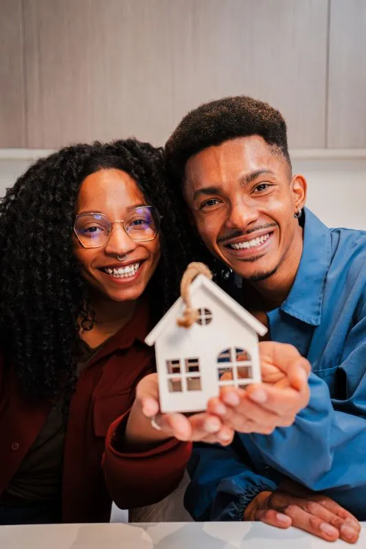 Un couple tient une petite maison