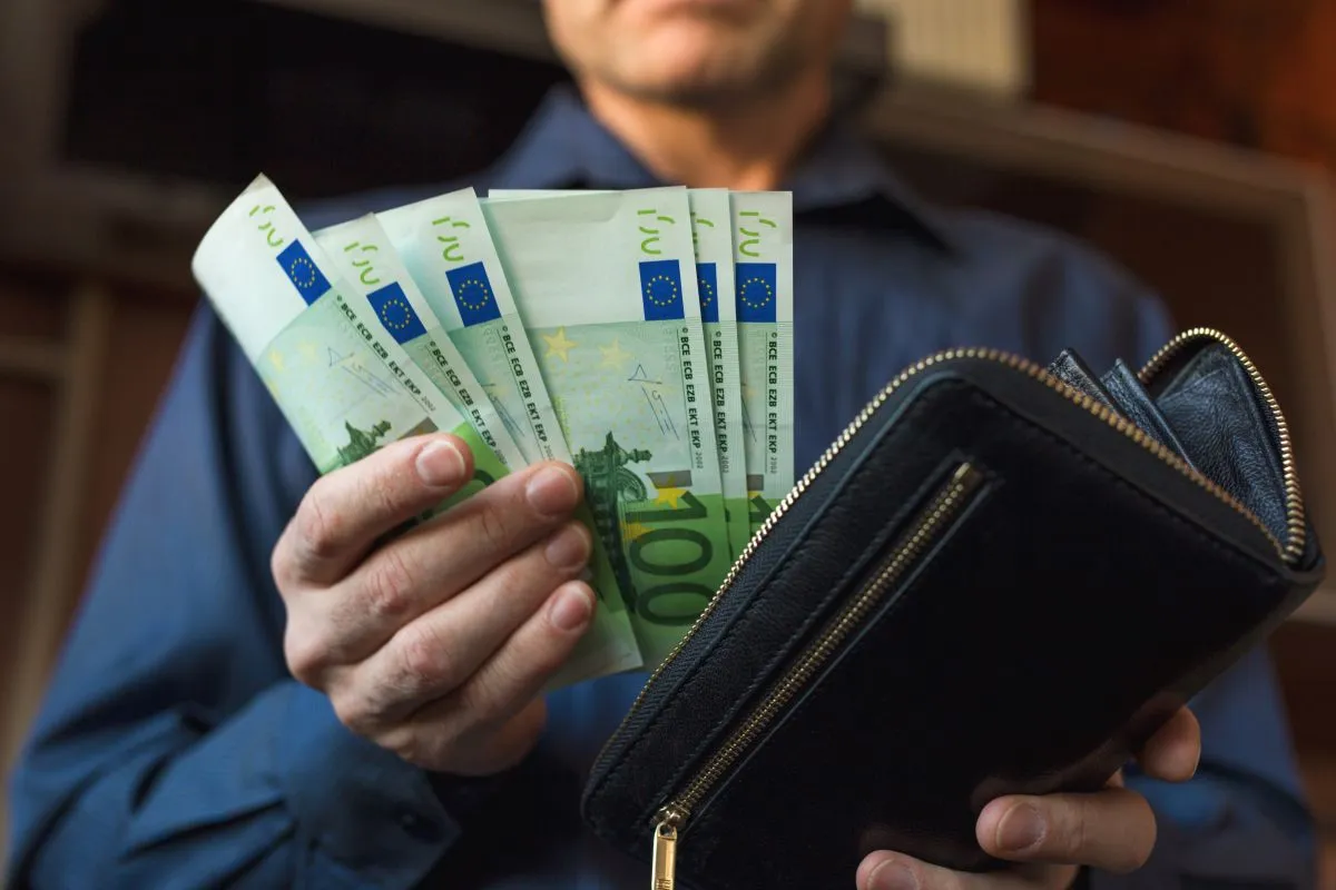 La main d'un homme prend de l'argent dans son portefeuille en mettant de l'argent