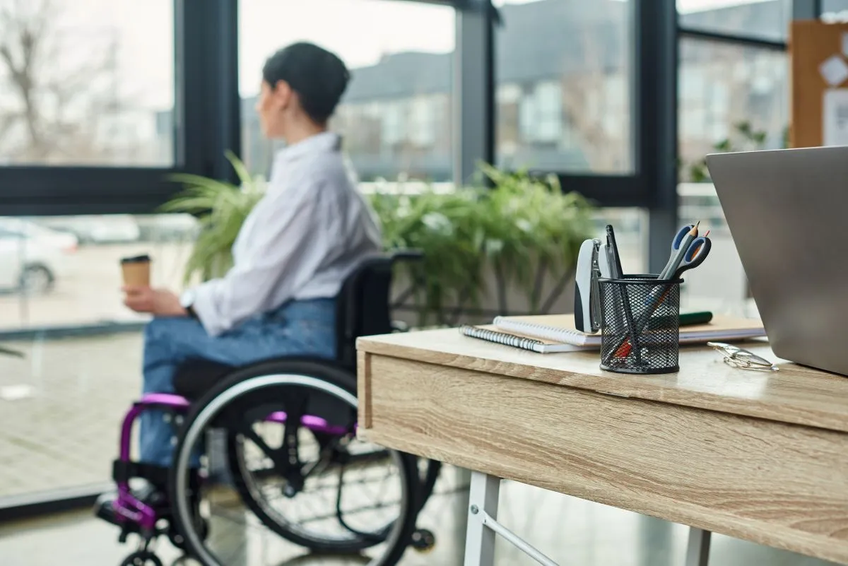 Une femme en fauteuil roulant regarde par la fenêtre