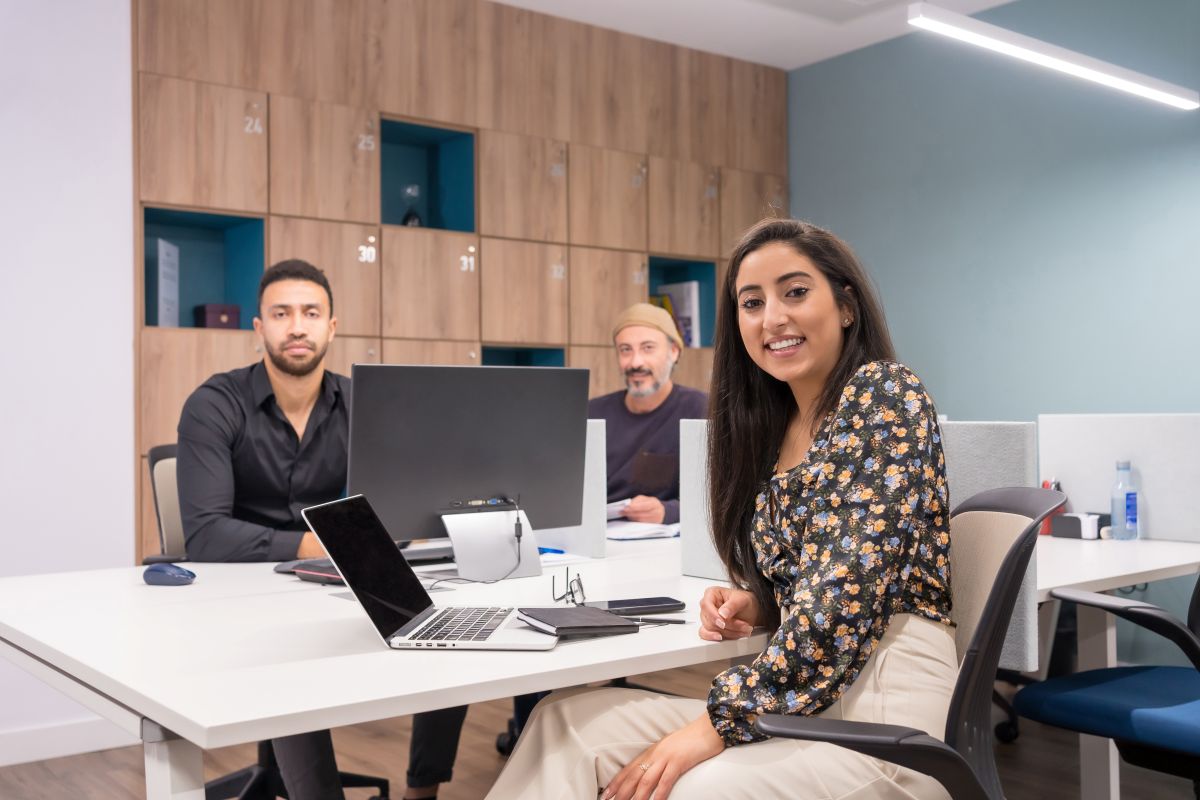 Trois collègues assis sur un bureau de coworking