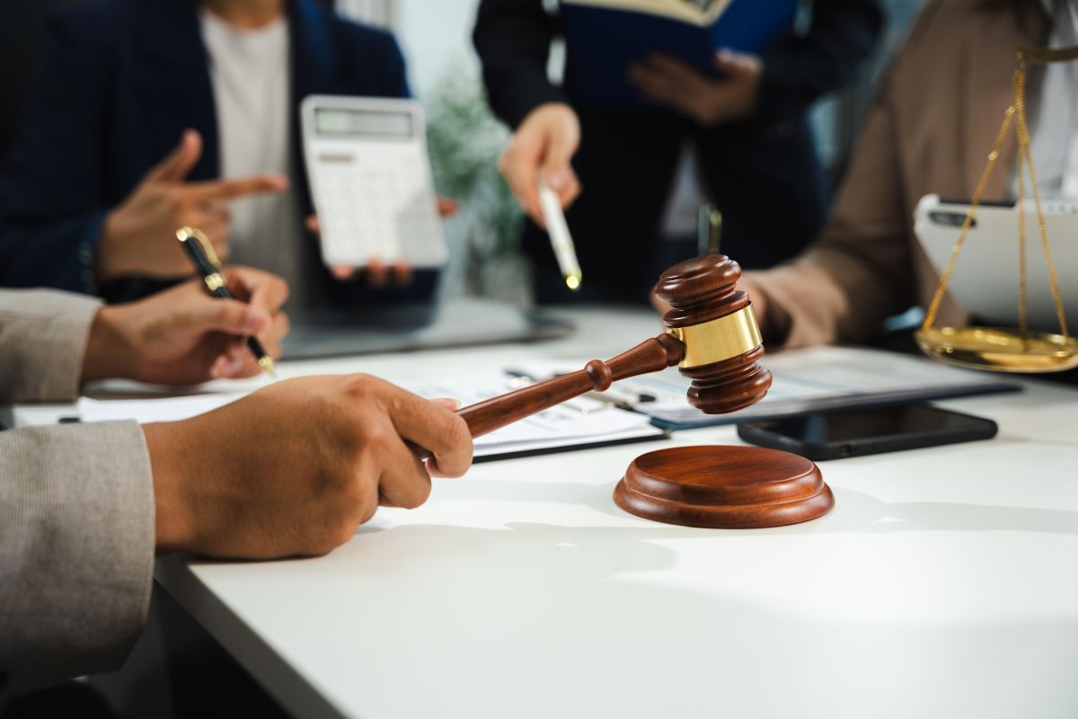 Des professionnels du droit autour d’un marteau de juge, avec une balance juridique en arrière-plan